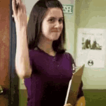 a woman in a purple shirt is holding a clipboard and giving a high five .