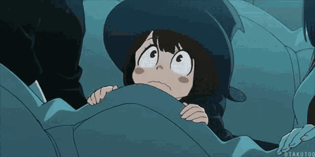 a girl in a witch hat is hiding under a blanket .