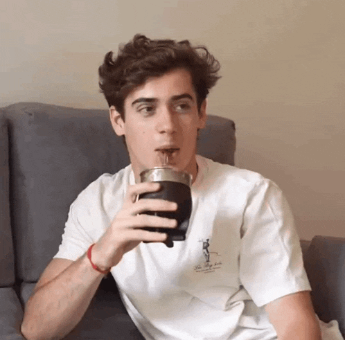 a young man is drinking from a cup that says the valley club