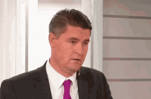 a man in a suit and tie is making a funny face .