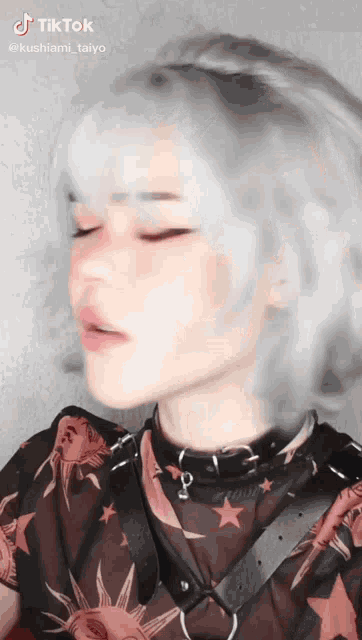 a woman with white hair is wearing a black shirt with stars on it and a choker around her neck