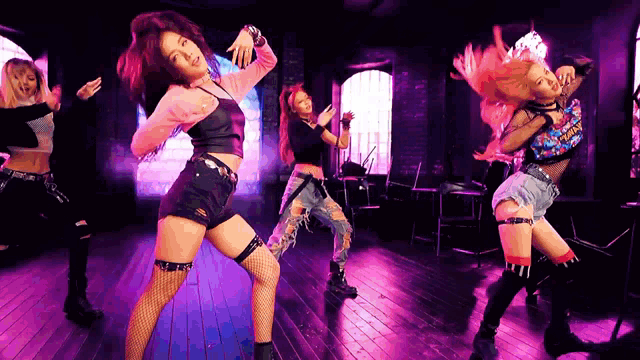 a group of women are dancing in a room with purple lights behind them