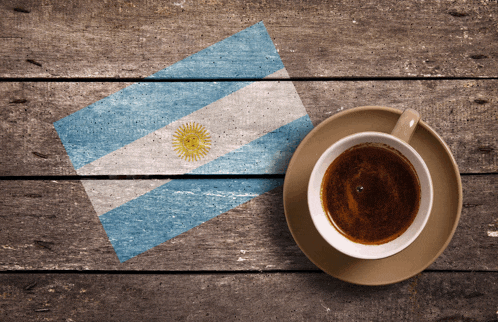 a cup of coffee sits on a saucer on a wooden table with a flag painted on it