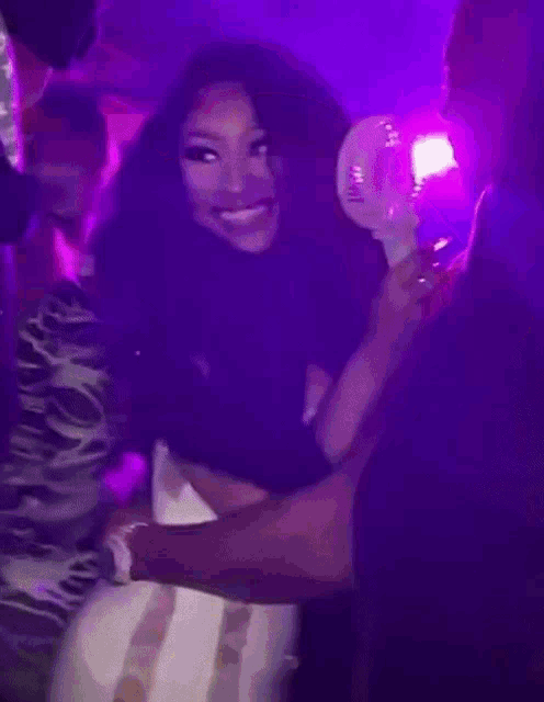 a woman in a white dress is hugging a man in a purple room while holding a light stick .