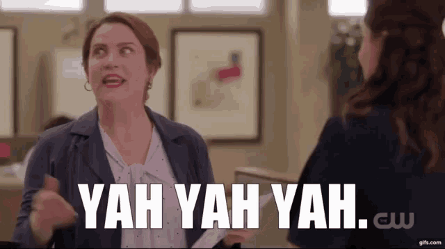 a woman is talking to another woman in an office while holding a piece of paper in her hand .