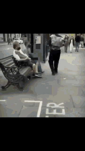 a man wearing a mask sits on a bench on a sidewalk next to a sign that says er