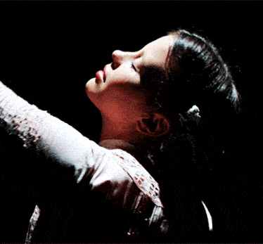 a woman with her eyes closed and her arms outstretched in the dark