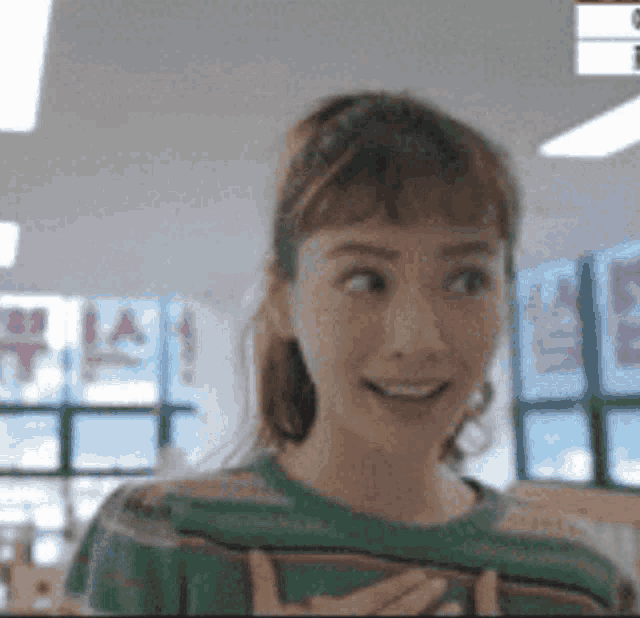 a woman in a green shirt is smiling in front of a sign that says ' a ' on it