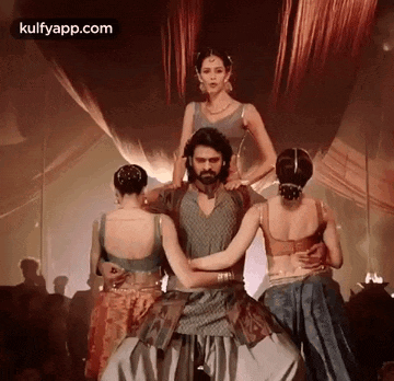 a man and two women are dancing together on a stage in a room .