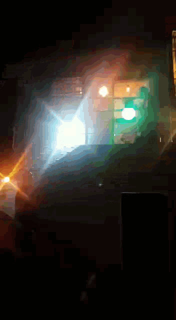 a car is driving down a street at night with a green light behind it