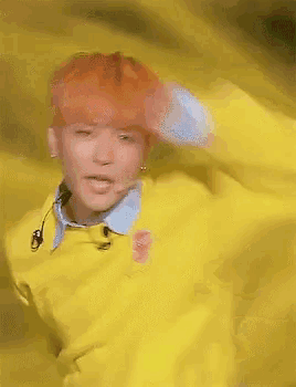 a person with red hair is wearing a yellow sweater and a blue shirt .