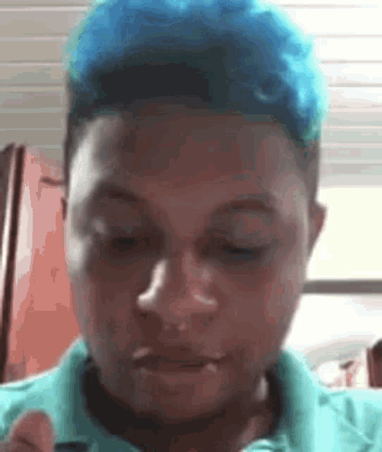 a young man with blue hair is wearing a blue shirt and eating a sandwich .