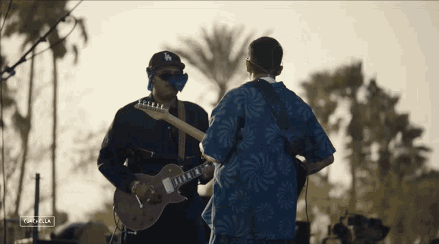 a man wearing a la hat is playing a guitar on stage