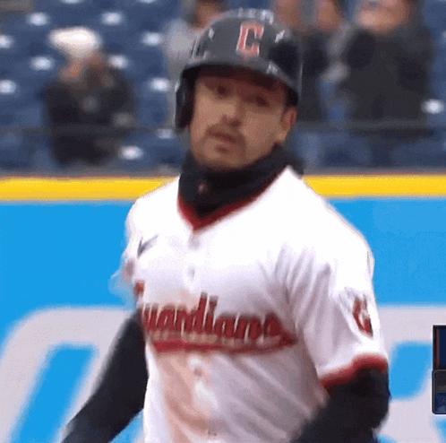a man in a guardians jersey stands on the field