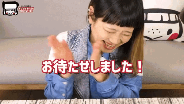 a girl sitting on a couch with her hands in the air and the words monster in red letters behind her