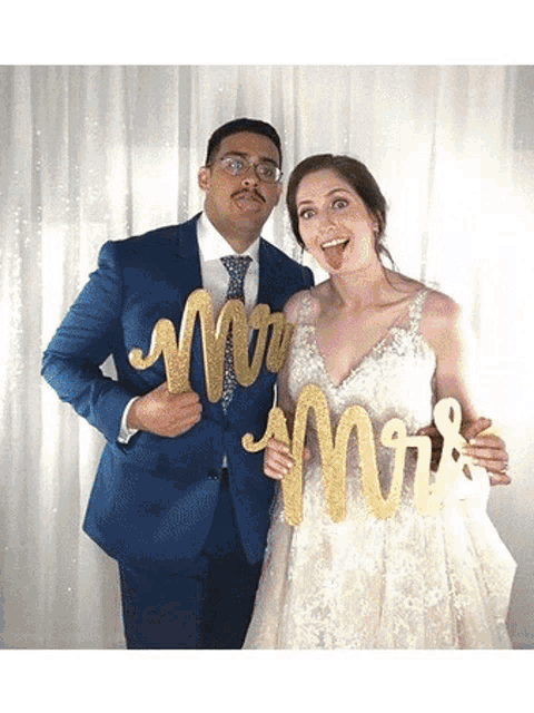 a bride and groom are posing for a picture in a photo booth holding mr. and mrs. signs