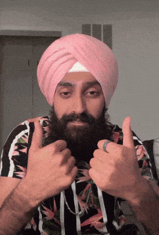 a man with a beard wearing a pink turban is giving a thumbs up sign