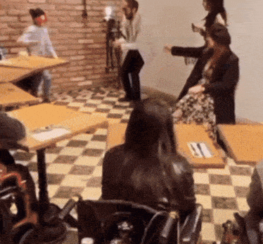 a woman in a wheelchair sits at a table in a room with other people