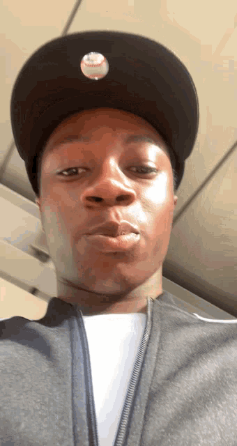 a man wearing a hat with a baseball on it looks at the camera