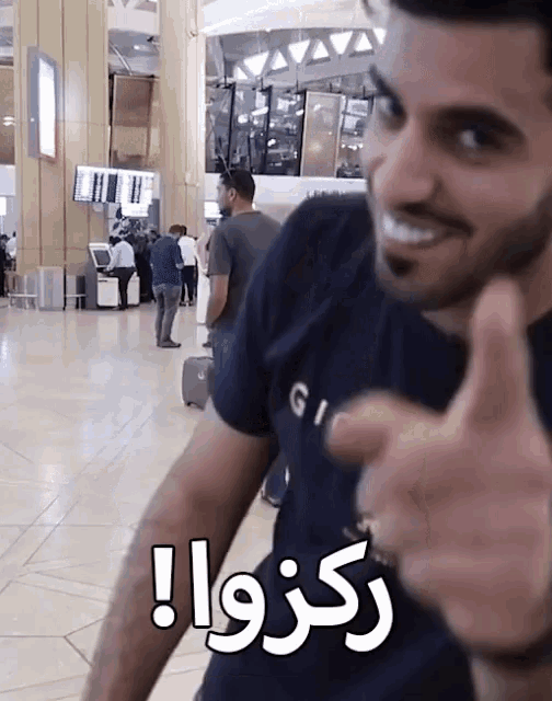 a man giving a thumbs up in front of a sign that says ' rkzwa '