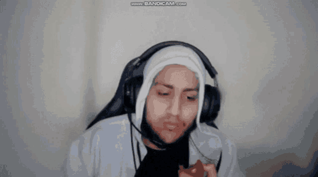a man wearing headphones and a hood is holding a tomato .