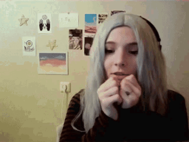 a woman wearing a wig and headphones looks at the camera