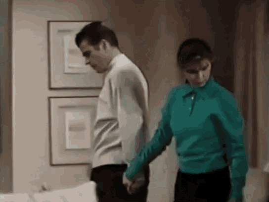a man and a woman are holding hands in a room .