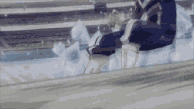 a person is sitting on a bench in a stadium with a blurred background .