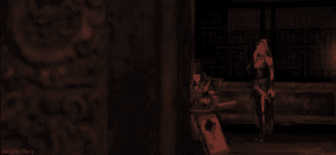 a woman is standing in a dark room holding a sword while a man sits at a table .