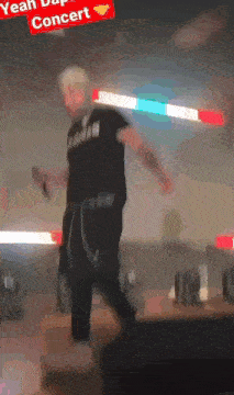 a man in a black shirt with the word yeah on it stands on a stage holding a microphone