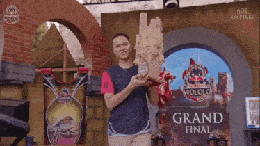 a man holds a trophy in front of a sign that says " grand final "