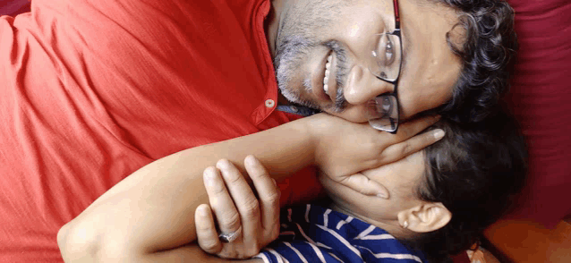 a man wearing glasses is laying on a woman 's chest