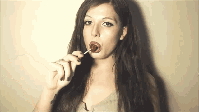 a woman with long hair is eating a lollipop
