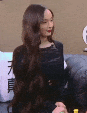 a woman with long hair is sitting on a couch in a room .