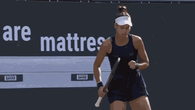 a woman holding a tennis racquet in front of a sign that says mattress