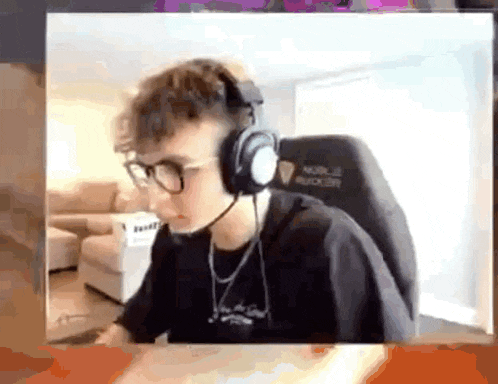 a young man wearing headphones and glasses is sitting in a chair in a living room .