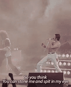 a man without a shirt is dancing on a stage in front of a crowd while another man plays a guitar .