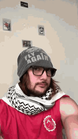 a man wearing glasses and a beanie that says fly again