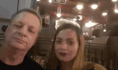 a man and a woman are posing for a picture in a restaurant