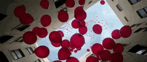 looking up at a bunch of red balloons floating in the air