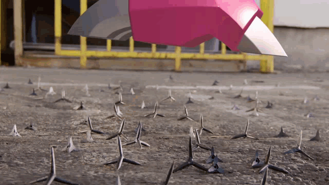 a bunch of spikes on the ground with a pink object flying in the background