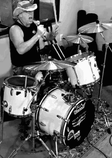 a man is playing drums in a black and white photo while wearing a cowboy hat .