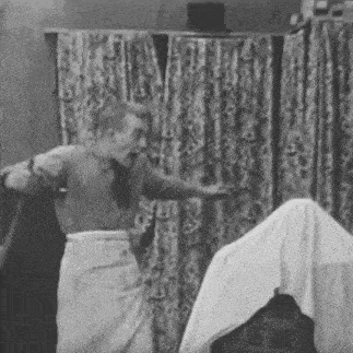 a black and white photo of a man standing next to a ghost covered in a sheet .