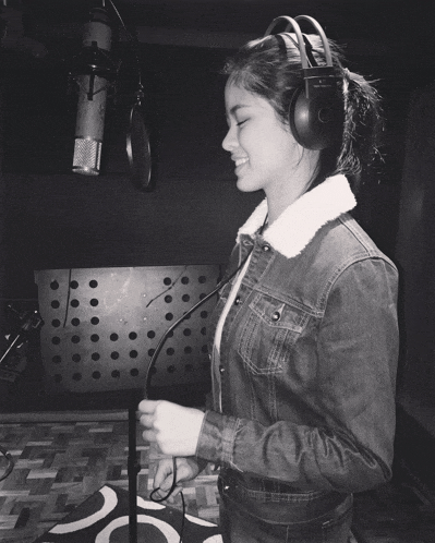 a woman in a denim jacket is singing into a microphone