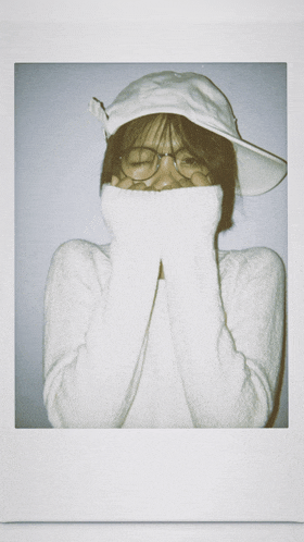 a woman wearing a white hat and glasses covering her face