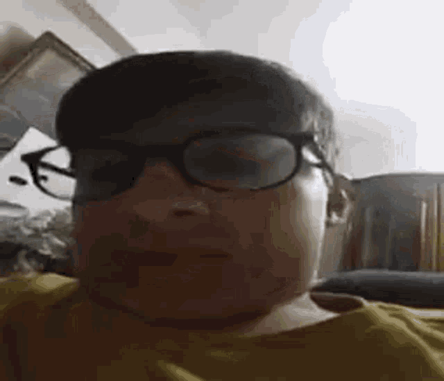 a young boy wearing glasses is sitting on a couch in a living room .