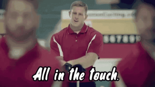 a man in a red shirt is standing in front of a group of men and says all in the touch