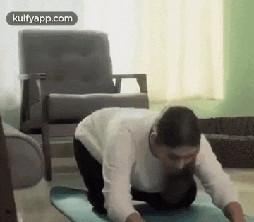 a woman is kneeling on a yoga mat in front of a chair .