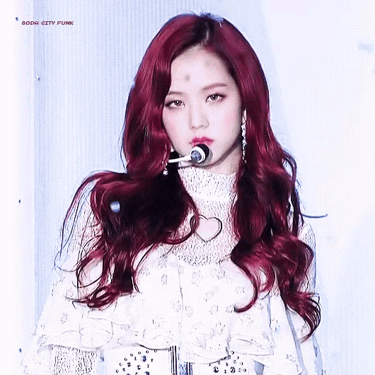 a woman with red hair is holding a microphone in her mouth .