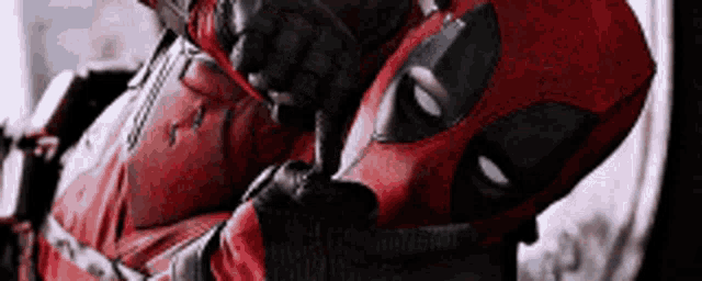 a close up of a deadpool holding his finger to his mouth .